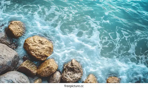 Foamy Ocean Water Surrounding Rocks on a Beach