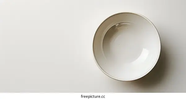 An empty bowl sits on a solid color background.