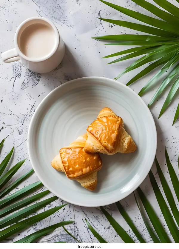 Freshly Baked Croissants with a Cup of Coffee and Green Leaves