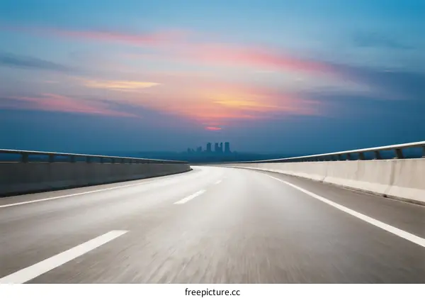 A scenic highway at sunset with city skyline in the distance
