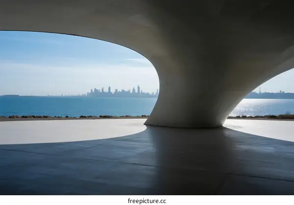 Modern architectural structure with sea view and city skyline in the distance