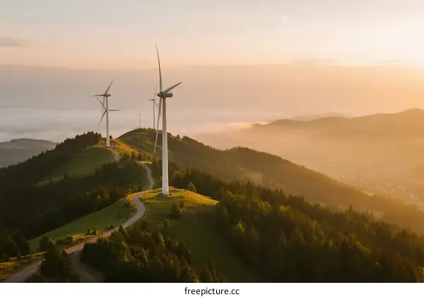 Wind turbines on a hill at sunrise with mist in the valley