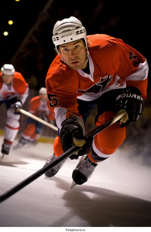 Ice hockey player in orange jersey skating fast on ice during a hockey game
