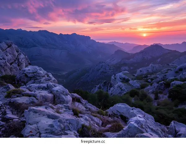 Mountain landscape with rocks in foreground and sunset in background