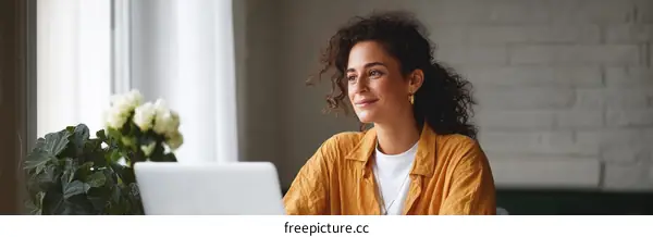 Woman working on laptop at home window