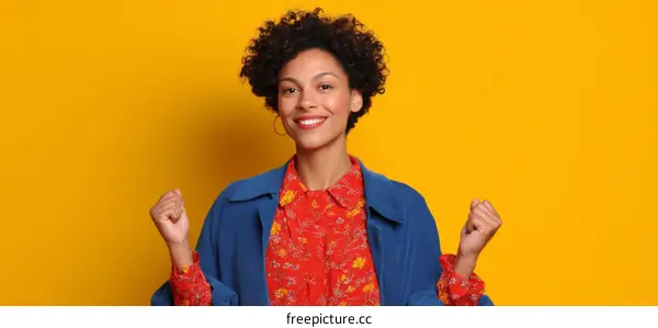 Happy Woman in Blue Coat and Red Blouse Against Yellow Background
