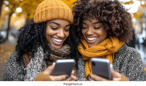 Two Black Women Friends Look At Phone And Smile