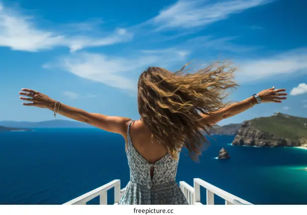 carefree woman standing on a cliff edge overlooking the mediterranean sea