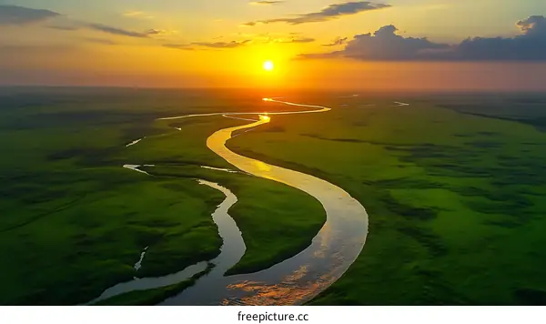 Sunset Over a Winding River Through Lush Green Plains