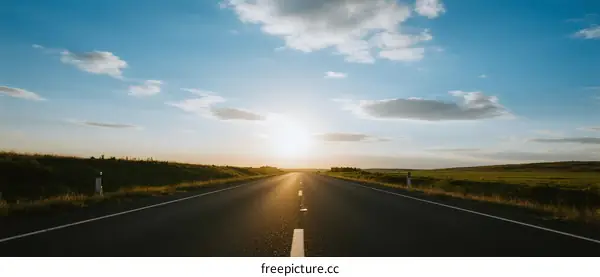 Sunset view of an empty road stretching under a clear blue sky