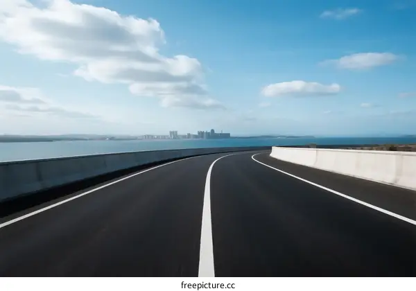 Smooth asphalt road stretching towards a scenic coastal view under a clear blue sky