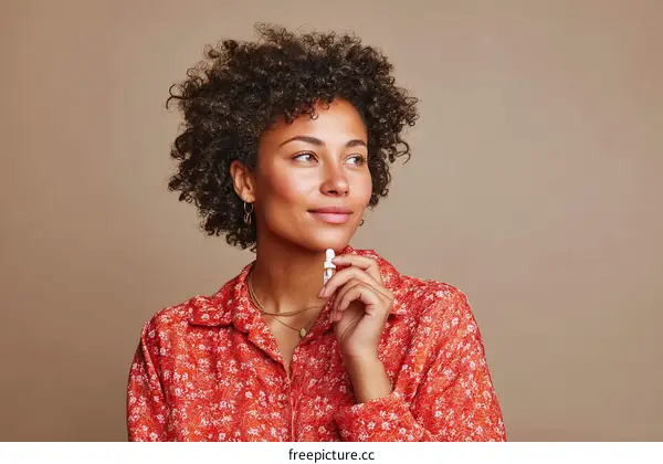 Young woman with curly hair wearing red floral shirt looking away