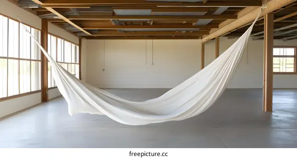 White Hammock Hanging in a Large Empty Room with Wooden Beams
