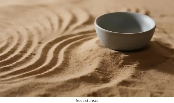 A Simple Ceramic Bowl Placed on Textured Sand with Ripple Patterns