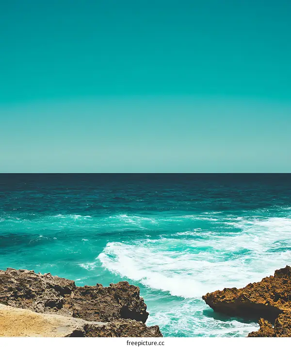 Ocean Waves Crashing on Rocks Under Blue Sky