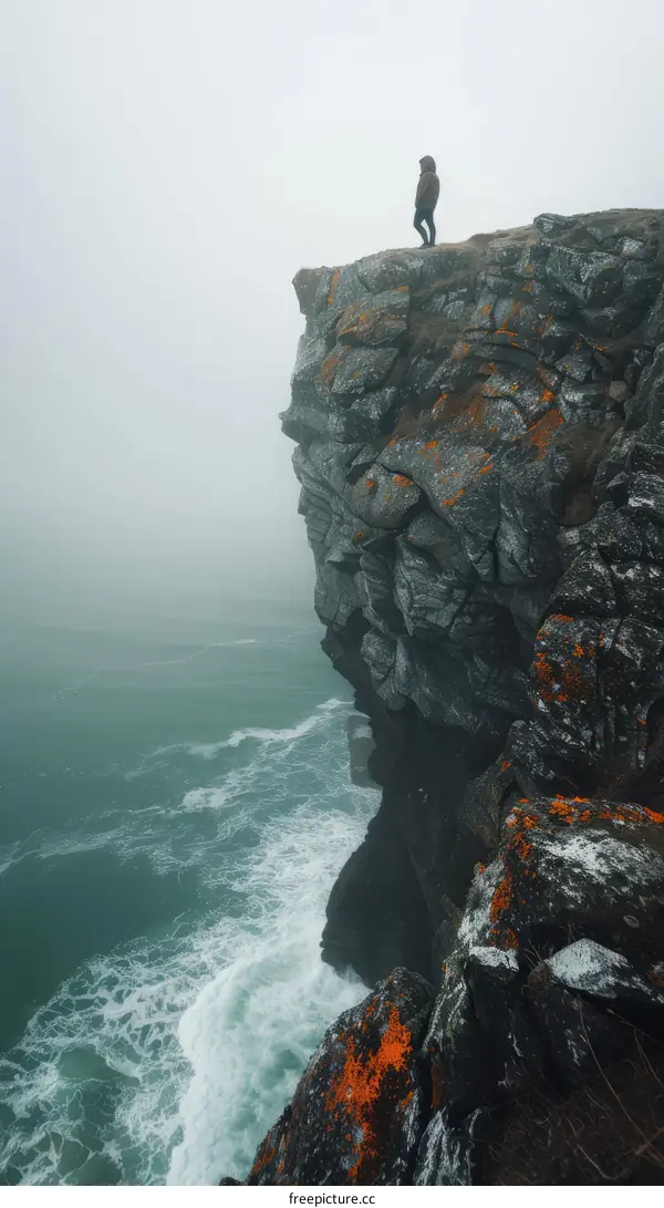 Man standing alone on a cliff overlooking a vast ocean