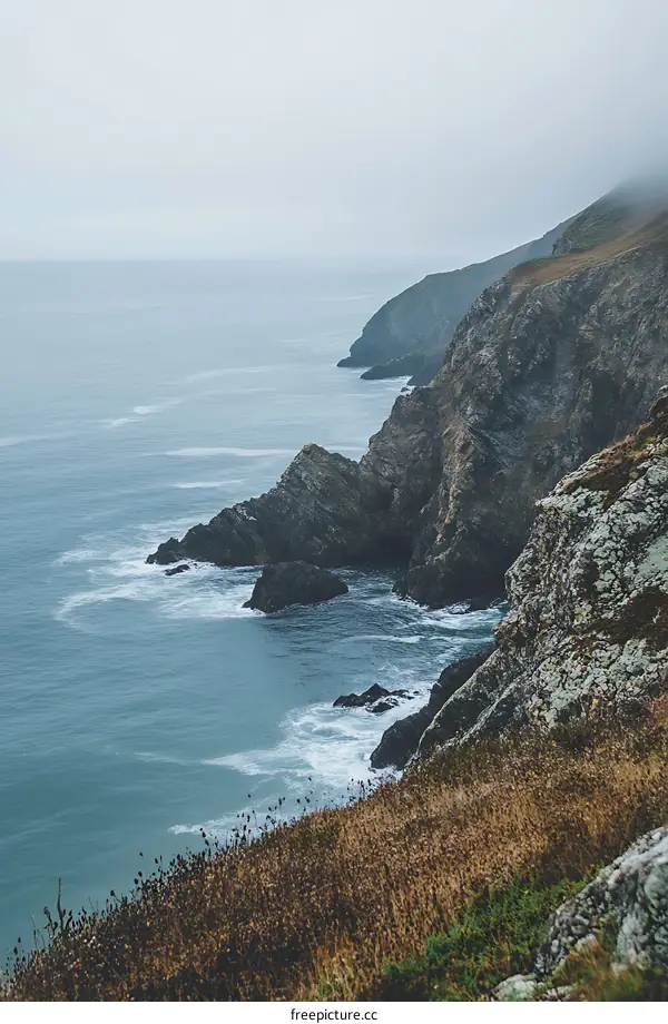 Rocky Coastline with Foggy Sky and Ocean Waves