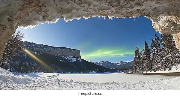 Frozen Cave View of Northern Lights Over Mountains