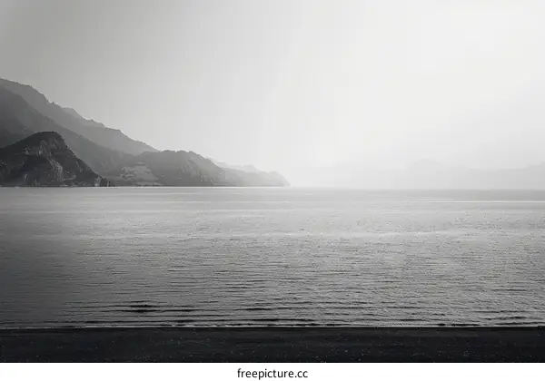 Serene Black and White Landscape: Calm Lake with Distant Mountains