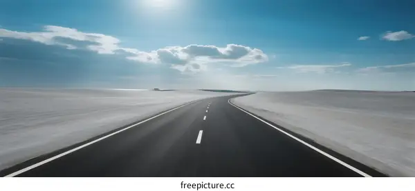 A Long Asphalt Road Stretching Under a Bright Blue Sky with Clouds