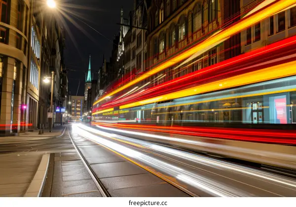 Light trails of a tram passing through a city street at night