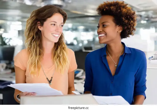 Two Women Colleagues Discussing Documents in Office