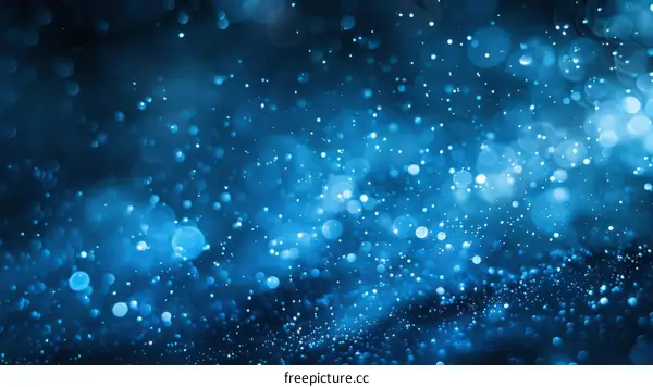 Blue abstract background with glitter and glowing particles