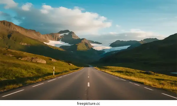 Scenic road through lush green mountains with snow patches