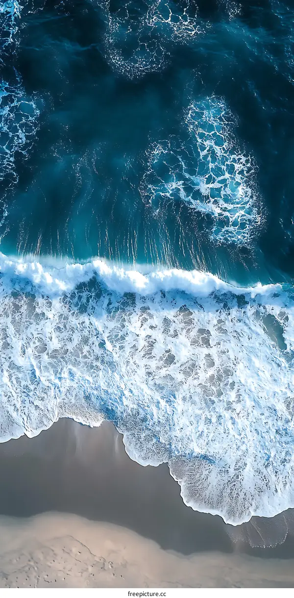 Aerial View of a Wave Crashing on a Sandy Beach