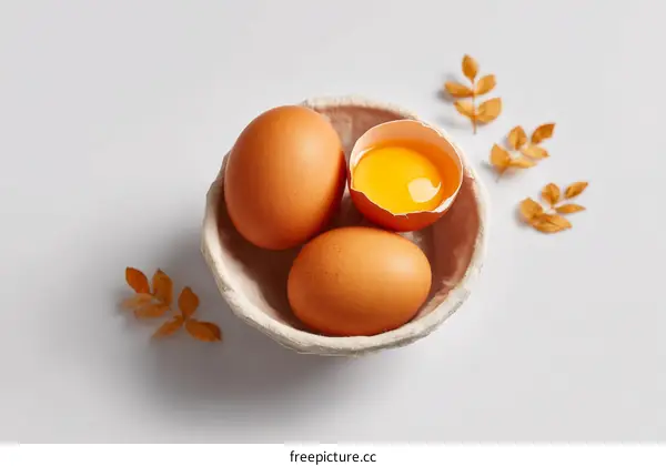 Three Brown Eggs in a Bowl with Autumn Leaves