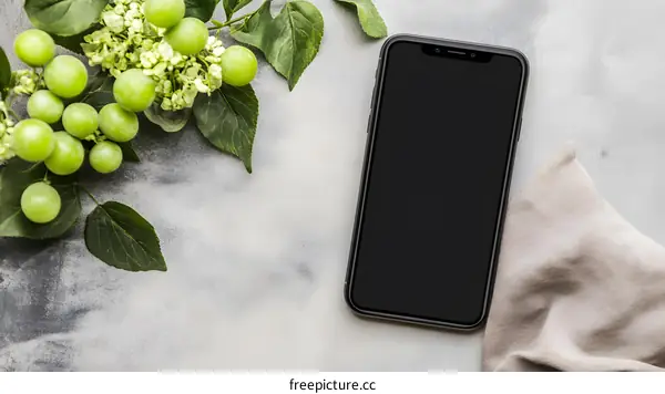 Black Smartphone with Green Leaves on a Grey Background