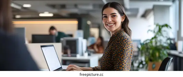 Smiling Woman Working on Laptop in Modern Office