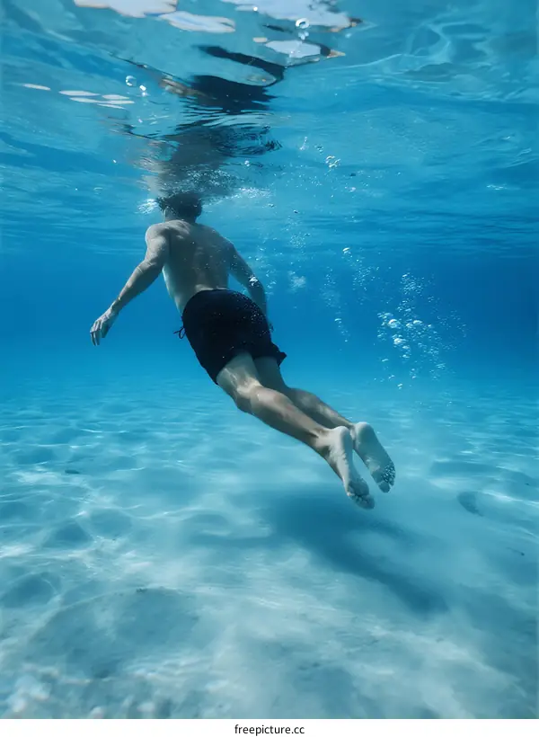 Man Swimming Underwater in Clear Blue Ocean Water