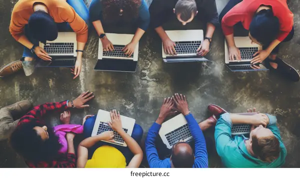 A group of diverse young people sitting on the floor and using laptop computers