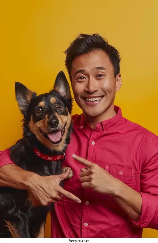 A smiling Asian man in a pink shirt poses with his dog