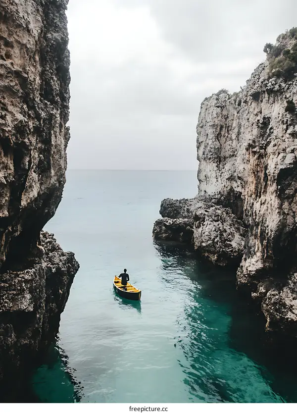 Man in a Boat Between Two Cliffs