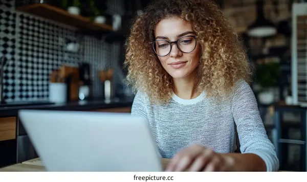Woman Working on Laptop in Kitchen