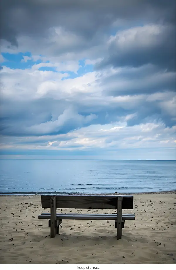 Lonely Bench on a Sandy Beach with Cloudy Sky