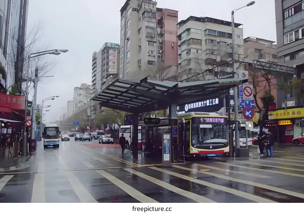 City Street with Bus Stop and People Walking in Rain