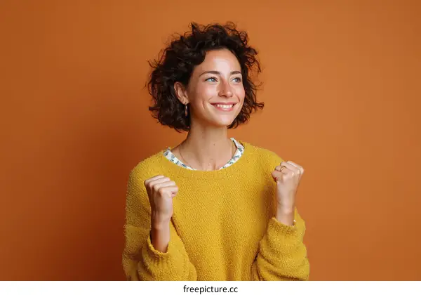 Smiling Woman Celebrating Success in Mustard Yellow Sweater