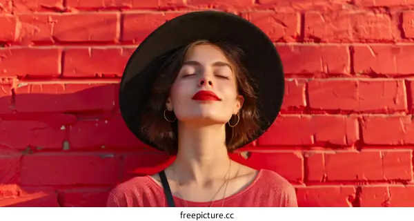 Young pretty woman with closed eyes standing near brick wall