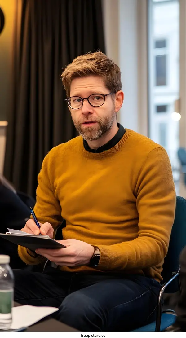 Man in Yellow Sweater Taking Notes in a Meeting