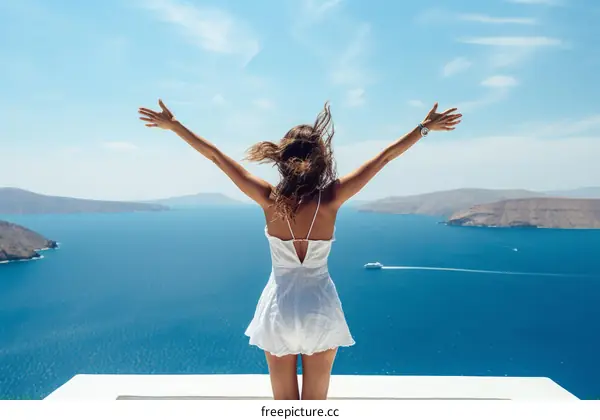 woman standing on a cliff edge with her arms outstretched enjoying the view of the mediterranean sea