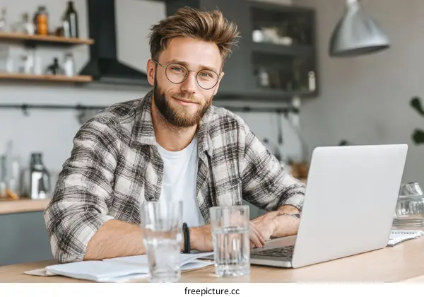 Young Caucasian Man Working on Laptop in Kitchen