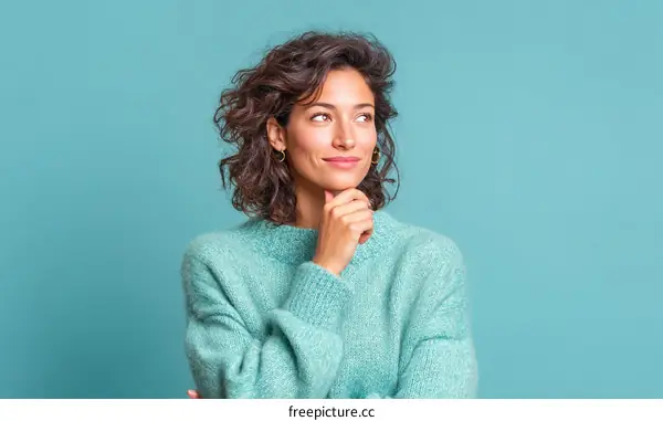 Thoughtful Woman in Teal Sweater Against Teal Background