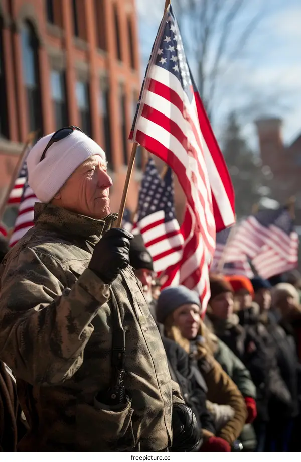 An elderly man holds an American flag at a rally.
