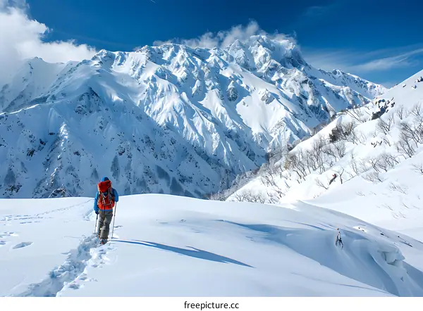 A lone hiker traverses a snowy mountain landscape