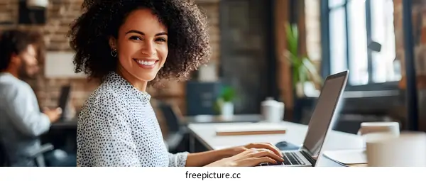 Smiling Woman Working on Laptop in Modern Office