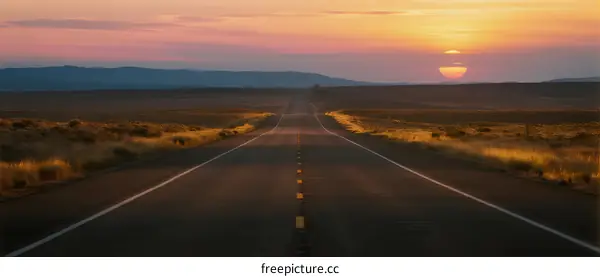 A long road stretching into the distance under the setting sun