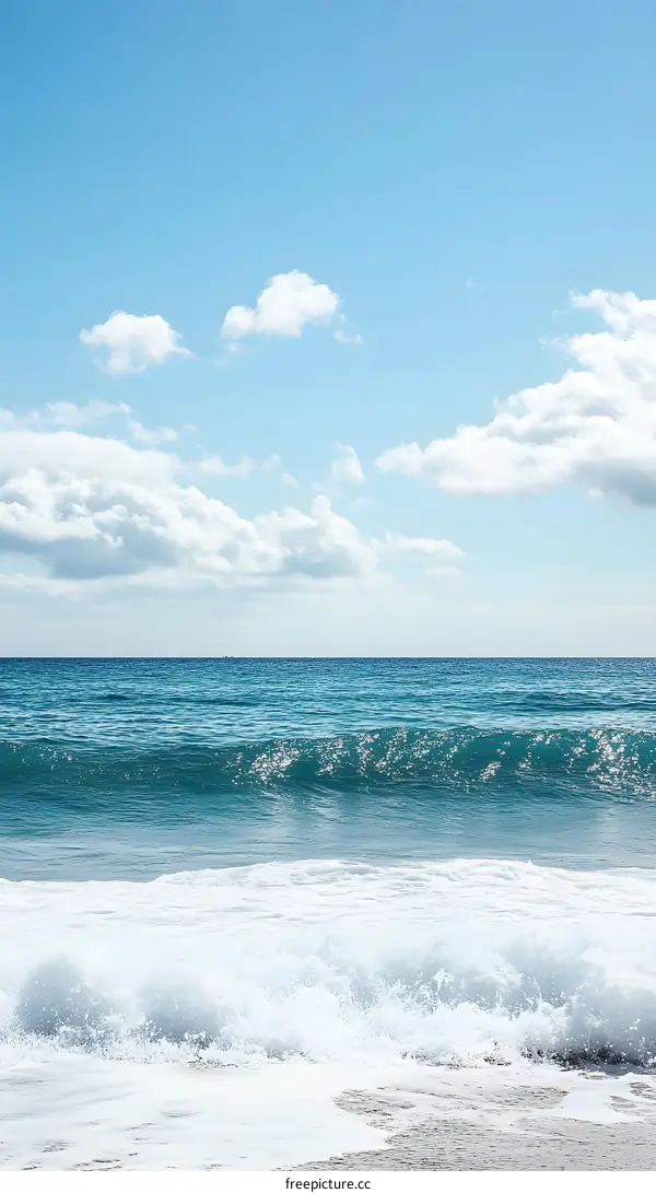 Azure Sky, White Clouds, and Ocean Waves Crashing on Sandy Shore